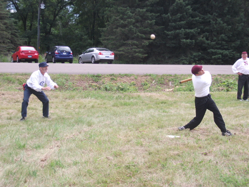 Northfield leads off the match with a foul ball while St. Croix Behind "Rufus" Nelson watches.